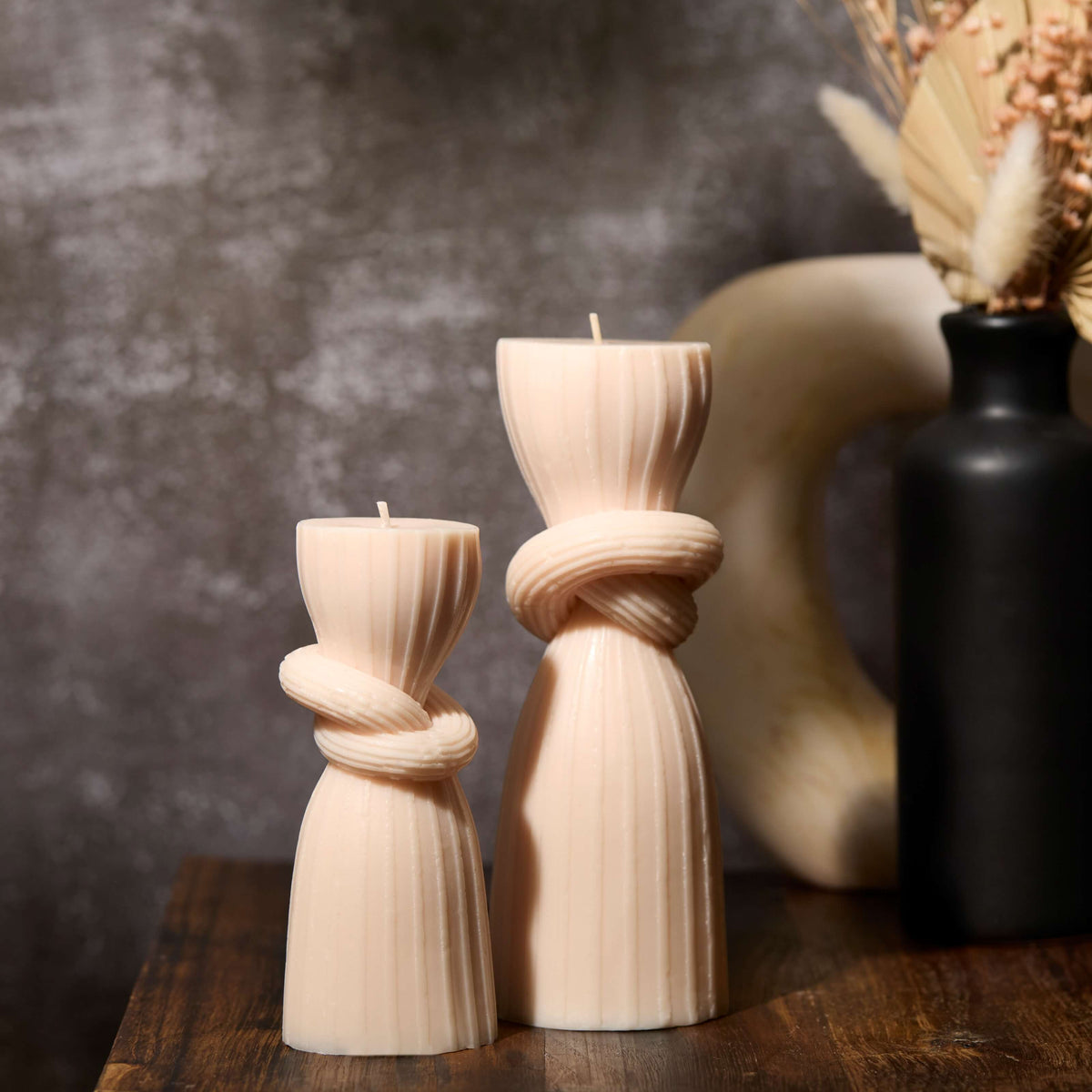 2 pillar candles sitting next to a vase
