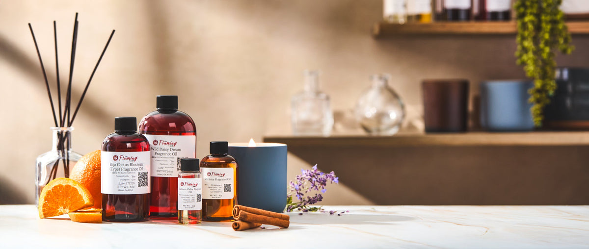 ChatGPT said: Bottles of The Flaming Candle fragrance oils with sliced oranges, cinnamon sticks, and lavender on a marble surface beside a lit candle. Shelves with jars and plants create a warm, inviting studio atmosphere.