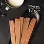 Wooden strips on a black plate with 'Extra Large' text and metallic objects on a dark background - Zoom Thumbnail Media 1